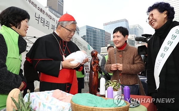 염수정 추기경(왼쪽 두 번째)이 3일 오후 서울 명동성당에서 열린 '낙태죄 폐지 반대를 위한 100만인 서명운동'에 참석해 서명한 뒤 6개월 반이 된 태아의 인형을 안아보고 있다. (출처: 연합뉴스)