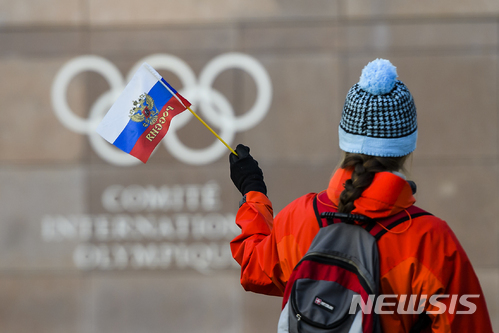 국제올림픽위원회(IOC)는 5일(현지시간) 스위스 로잔에서 집행위원회를 열고 내년 평창 동계올림픽에서 러시아 선수들의 개인 출전은 허용하지만 선수단 출장은 금지했다. 이날 러시아 국기를 든 한 여성이 IOC 본부를 바라보고 있다. (출처: 뉴시스) 2017.12.06.