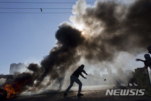 지난 8일(현지시간) 팔레스타인 자치지역인 요르단강 서안 라말라에서 시위자들이 타이어를 불태우고 돌을 던지고 있다. 이날 시위는 지난 6일 도널드 트럼프 미국 대통령이 예루살렘을 이스라엘의 수도로 인정한다고 발표한 데에 항의하기 위해 열렸다. (출처: 뉴시스)