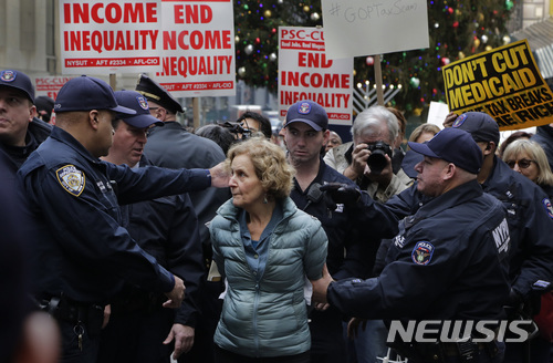 미국 뉴욕의 증권거래소 앞에서 19일(현지시간) 한 여성이 도널드 트럼프 대통령이 추진하고 있는 세제개편안에 반대하는 시위에 참여했다가 경찰에 체포되고 있다. (출처: 뉴시스)