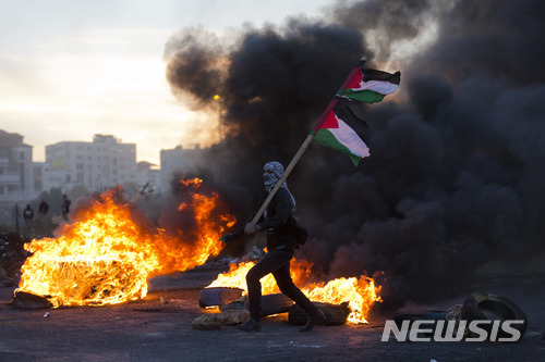 지난 10일 요르단강 서안 라말라에서 미국이 예루살렘을 이스라엘의 수도라고 인정한데 항의하는 시위가 열린 가운데 한 팔레스타인 청년이 팔레스타인 깃발을 휘두르고 있다. (출처: 뉴시스)