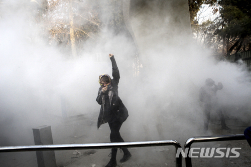 지난 해 12월 30일 이란 테헤란 대학에서 한 대학생이 최루탄을 발사하는 경찰을 향해 팔을 올려 주먹을 쥐어 보이고 있다. (출처: 뉴시스)