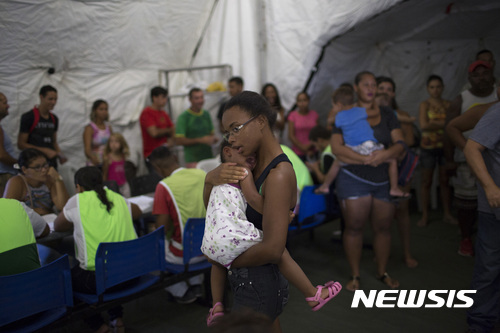 지난 3월 브라질의 황열병 집중 발생 지역인 리우데자네이루 주의 소도시 카시미로 데 아브레우에 임시로 마련된 천막 병원에서 주민들이 아이들을 안고 와 백신 접종을 하고 있다. (출처: 뉴시스)