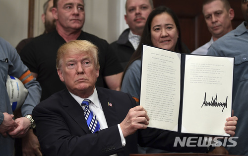 트럼프 대통령이 8일(현지시간) 오후 백악관에서 철강 업계 노동자와 노조 인사들이 참석한 가운데 ‘미 무역확장법 232조’를 근거로 한 고율관세 부과명령에 서명하고 들어 보이고 있다. (출처: 뉴시스)