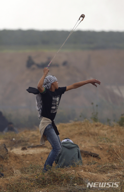 【가자=AP/뉴시스】 30일 '땅의 날'을 맞아 가자 봉쇄펜스 부근의 행진시위에 나선 팔레스타인 젊은이가 이스라엘 군인에게 돌 팔매질을 하고 있다. 2018. 3. 30. (출처: 뉴시스)