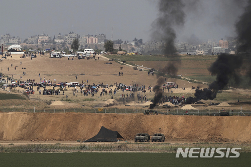 6일(현지시간) 이스라엘과 가자 경계선에서 가자 지구의 팔레스타인인 시위대가 '고향땅 귀환' 행진에 나서며 봉쇄선 가까이서 타이어를 태우고 있다. 봉쇄 펜스 아래에 이스라엘 군인 차량이 보인다. (출처: 뉴시스)