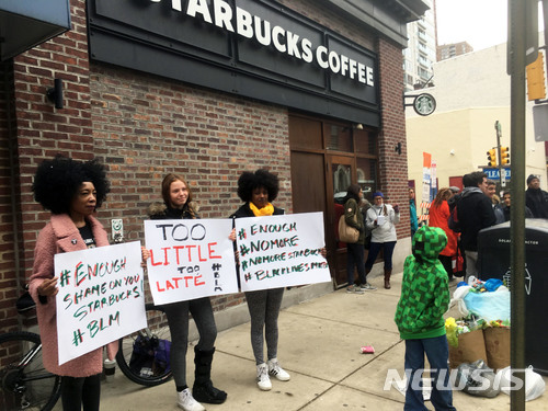 지난 12일 미 펜실베이니아주 필라델피아의 스타벅스 매장에서 흑인 남성 2명이 경찰에 체포된 것이 인종차별이라는 비난이 거세게 이는 가운데 이에 항의하는 시위대가 15일(현지시간) 이들이 체포된 스타벅스 매장 앞에서 피켓을 들고 시위를 벌이고 있다. (출처: 뉴시스)