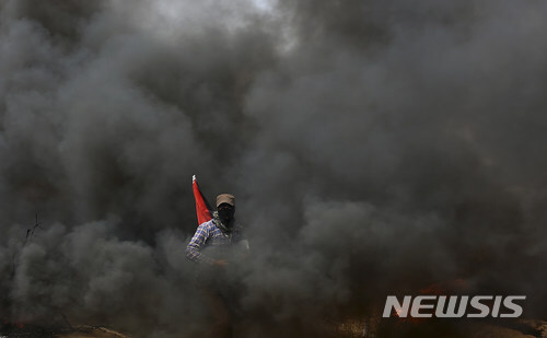 【가자시티=AP/뉴시스】팔레스타인 가자지구에서 20일(현지시간) 이스라엘군과 팔레스타인 시위대 간 충돌로 4명이 숨지고 150여 명이 다쳤다. 복면을 한 팔레스타인 시위자가 타이어를 불태우면서 생긴 검은 연기 속에 서있다. 2018.04.21 (출처: 뉴시스)