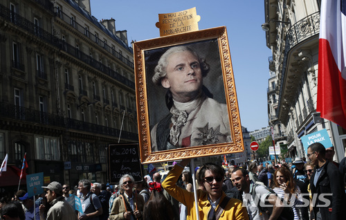 5일(현지시간) 에마뉘엘 마크롱 프랑스 대통령 취임 1주년을 맞아 파티와 피크닉 등 축제 분위기의 항의시위에 나선 파리 시민들이 마크롱을 루이 16세에 비유하며 왕의 초상화를 들고 행진하고 있다. (출처: 뉴시스)