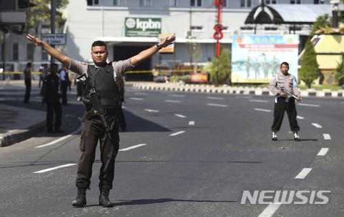 인도네시아 경찰이 14일 경찰서 앞에서 자살폭탄테러가 벌어진 동자바주 수라바야의 경찰서 앞 도로를 차단한 채 경계를 서고 있다. (출처: 뉴시스)
