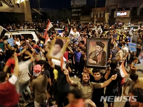 이라크 수도 바그다드의 타흐리르 광장에서 14일(현지시간) 시아파 성직자 무크타다 알-사드르의 초상화를 든 지지자들이 환호하고 있다. 알 -사드르 정당은 지난 12일 실시된 이라크 총선 초기 개표 결과 예상보다 좋은 성적을 거둔 것으로 나타났다. (출처: 뉴시스)