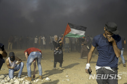 【가자=AP/뉴시스】 한 팔레스타인 여성이 15일(현지시간) 팔레스타인 가자지구에서 팔레스타인 국기를 미국의 대사관 이전에 항의하는 시위를 벌이고 있다. 이날 이스라엘군이 팔레스타인 시위대에 실탄을 발사하면서 60여명이 숨지고 2700여명의 부상자가 발생했다.