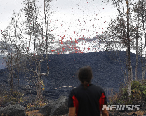 (AP Photo/뉴시스) 18일(현지시간) 미국 하와이주 하와이섬 파호아 지역 인근에서 아베 페드로가 화산재가 흩날리는 것을 보고 있다. 전날 하와이섬 동단 킬라우에아 화산(해발 1250ｍ)이 폭발을 일으키며 화산재를 분출해 무려 3만 피트(9100ｍ)에 달하는 거대한 가스 기둥이 정상부 상공으로 치솟았다고 하와이뉴스나우 등 현지언론이 보도했다.