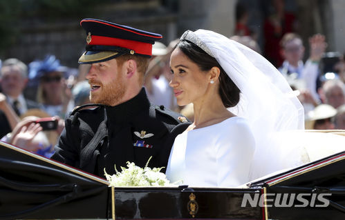 19일(현지시간) 영국 윈저성에 있는 세인트 조지 교회에서 결혼식을 마친 해리 왕자와 메건 마클이 대중들에게 인사하기 위해 지붕없는 마차를 타고 시내를 돌고 있다. (출처: 뉴시스)