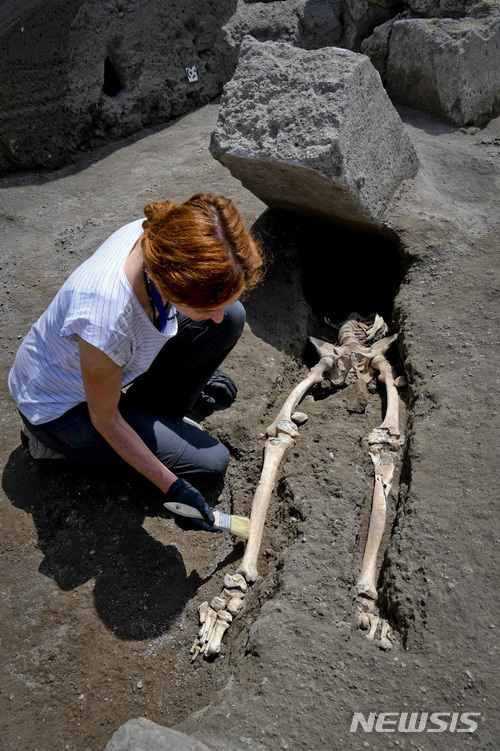 29일(현지시간) 한 고고학자가 폼페이 유적지에서 서기 79년 베수비우스 화산 폭발 당시 사망한 것으로 추정되는 유해를 살피고 있다. 유해 주인은 보행장애로 현장에서 변을 당한 것으로 추정된다. (출처: 뉴시스)