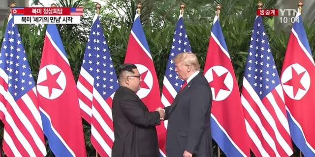 김정은 북한 국무위원장(왼쪽)과 도널드 트럼프 미국 대통령이 12일 오전 10시(한국시간) 싱가포르 센토사섬 카펠라 호텔 로비에서 만나 악수하고 있다. (출처: YTN 캡처)