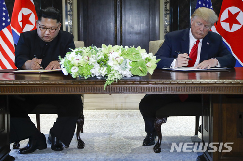 김정은 북한 국무위원장(왼쪽)과 도널드 트럼프 미 대통령이 12일 싱가포르 카펠라 호텔에서 사상 첫 북미 정상회담을 마친 뒤 합의문에 서명하고 있다. (출처: 뉴시스)