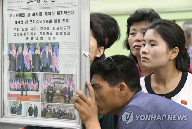 (평양 교도=연합뉴스) 싱가포르에서 역사적인 북미 정상회담이 열린지 하루가 지난 13일 북한 평양의 한 지하철역 신문 게시 코너에 뉴스를 보려는 시민들이 몰려들었다.