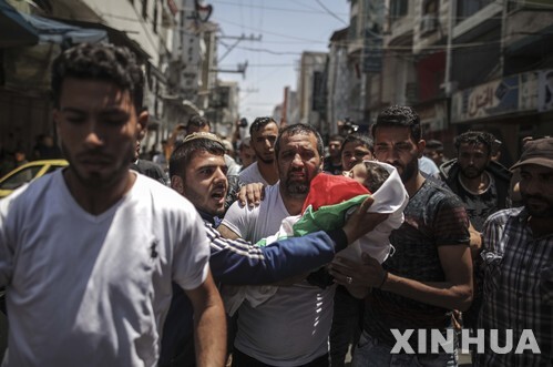 지난 5월 가자지구에서 하루 전 팔레스타인인들의 항의 시위 때 이스라엘군이 발사한 최루가스를 흡입해 사망한 생후 8개월 된 라일라 알-간두르의 시신을 안은 친척 등 추모객들이 장례식을 치르기 위해 걸어가고 있다. (출처: 뉴시스)