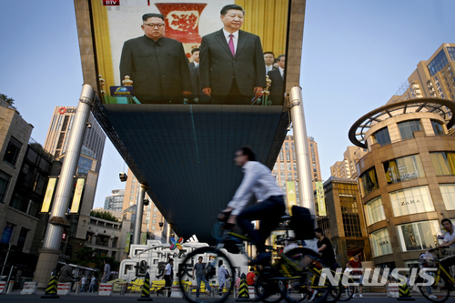19일 중국 베이징 시내에 설치된 초대형 TV 전광판에 이날 중국을 방문한 김정은 북한 국무위원장이 인민대회당 환영식에서 시진핑 중국 주석과 나란히 서 있는 장면이 방송보도되고 있다. (출처: 뉴시스)
