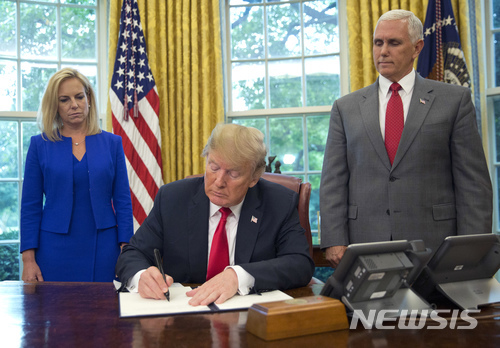 【워싱턴=AP/뉴시스】도널드 트럼프 미국 대통령(가운데)이 20일(현지시간) 불법이민 가족 분리 정책을 중단하기 위한 행정명령에 서명하고 있다.