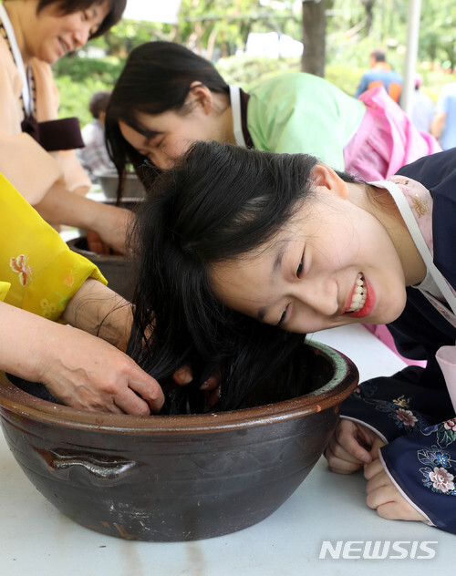 【서울=뉴시스】 단오축제가 열린 23일 오전 서울 영등포구 영등포공원에서 한복을 곱게 차려 입은 학생들이 창포물 머리감기 체험을 하고 있다.
