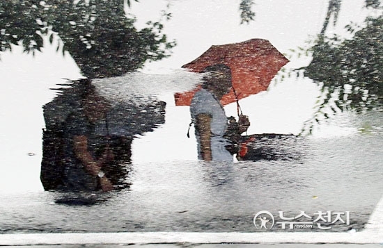 소나기가 내린 25일 오후 서울역 앞 물 웅덩이에 우산을 쓴 채 지나가는 시민의 모습이 비치고 있다. ⓒ천지일보(뉴스천지)