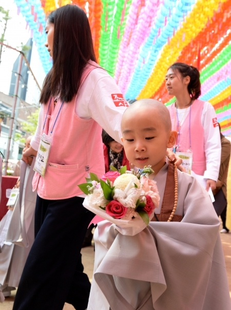 지난 5월 22일 부처님 오신 날을 맞아 동자승이 법당에 올릴 꽃을 들고 걸어가고 있다. (출처: 뉴시스)