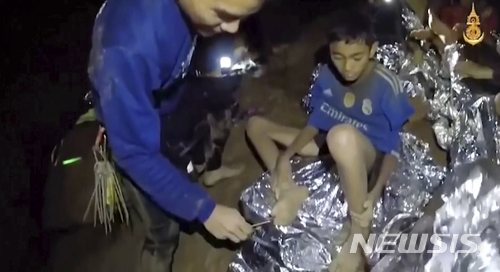 태국 해군 특수부대 네이비실 대원 한명이 소년 한명을 치료해주고 있는 모습. (출처: 뉴시스)
