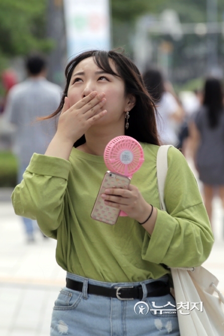 폭염주의보가 발령된 25일 오후 서울시청 인근 거리에서 한 시민이 휴대용 선풍기로 더위를 식히고 있다. ⓒ천지일보(뉴스천지)