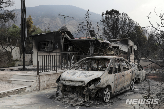 대형 산불이 발생한 그리스 아테네의 키네타 마을의 한 불타버린 집 앞에 24일(현지시간) 타다 남은 자동차 한 대가 놓여 있다. (출처: 뉴시스)