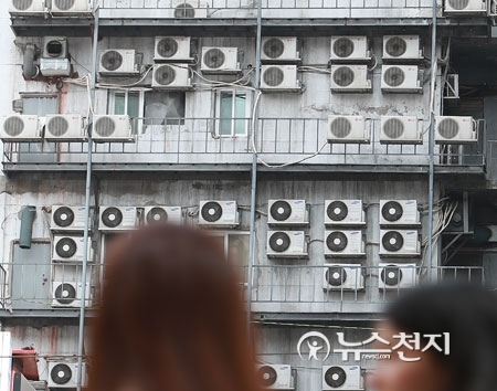 장마전선의 영향으로 폭염 속 습도가 높아져 후텁지근한 날씨를 보인 18일 오후 시민들이 서울 남대문로에 에어컨 실외기로 가득 찬 외벽 앞을 지나가고 있다. ⓒ천지일보