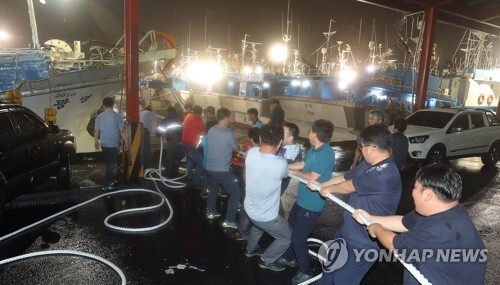 (서귀포=연합뉴스) 제주도 전역에 태풍경보가 내려진 22일 오후 서귀포항에서 어민들이 배들을 단단히 고정하기 위해 힘을 모아 로프를 당기고 있다.