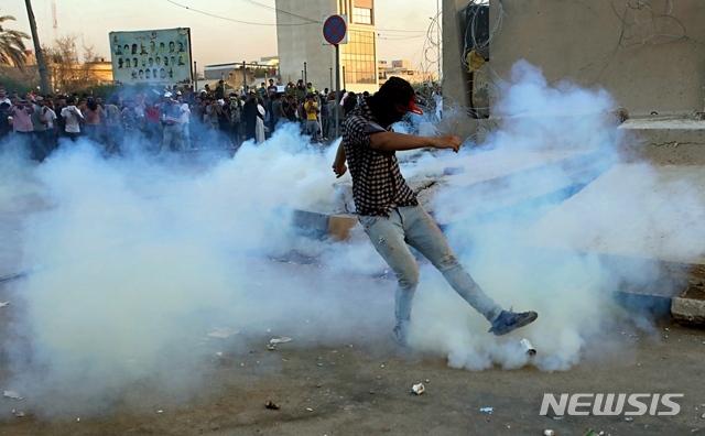 (AP Photo/뉴시스) 최근 이라크 남부 유전지대 바스라 주에서 민생고 시위가 수도 바그다드로 북상한 가운데 지난달 31일(현지시간) 바그다드 바스라에서 가면을 쓴 시위대가 최루 가스통을 차고 있다.