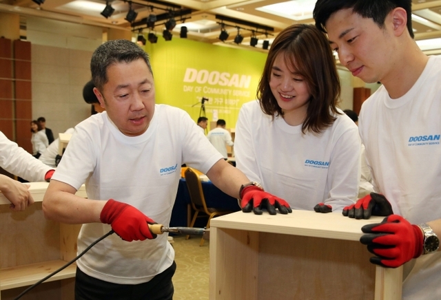 박정원 두산그룹 회장(왼쪽)이 4월 25일 열린 ‘Doosan Day of Community Service(두산인 봉사의 날)’ 행사에서 지역사회 취약계층 가정에 보급될 가구 제작에 나서고 있다.  (제공: 두산그룹)