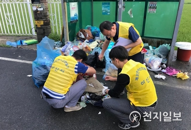 지난달 아산시 단속반원들이 불법 투기된 쓰레기에서 증거물을 찾고 있다. (제공: 아산시) ⓒ천지일보 2018.9.3