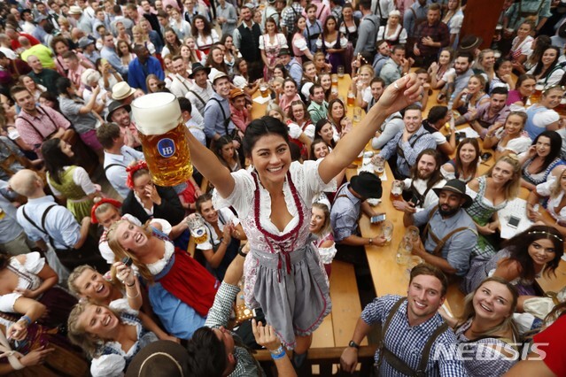 【뮌헨(독일)=AP/뉴시스】독일 뮌헨에서 185회 옥토버페스트가 개막한 22일 한 젊은 여성이 맥주를 든 채 테이블 위에 올라서 전세계 최대 맥주 축제의 개막을 축하하고 있다.