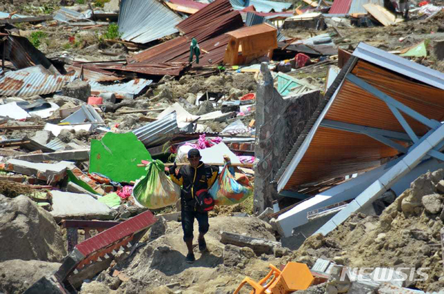 인도네시아 술라웨시주 팔루에서 1일 한 남성이 무너진 건물더미를 뒤져 찾아낸 쓸만한 물건들을 나르고 있다. 844명의 목숨을 앗아간 지난달 28일의 강진과 쓰나미 발생 후 4일만인 2일 인도네시아 남부 플로레스섬 인근에서 규모 5.9의 지진이 또 일어났다. 쓰나미 경보는 내려지지 않았고 인명 피해는 아직 보고되지 않고 있다. (출처: 뉴시스)