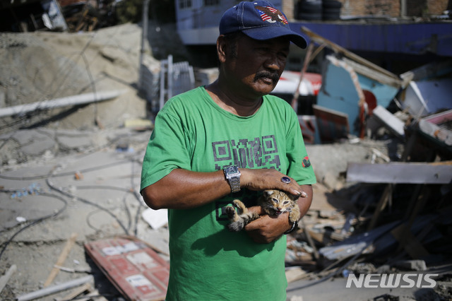 【발라로아=AP/뉴시스】인도네시아 술라웨시 섬 발라로아에서 2일 사아돈 라위라란 이름의 남성이 지진으로 무너진 집 잔해더미에서 손자의 고양이를 구해내 쓰다듬고 있다.
