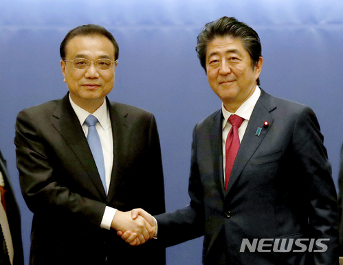리커창 중국 총리(왼쪽)와 아베 신조 일본 총리가 11일 홋카이도 삿포로에서 열린 포럼에 참석해 악수하고 있다. (출처: 뉴시스)