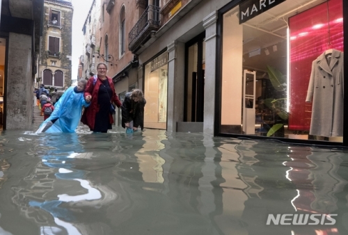29일(현지시간) 이탈리아 베네치아에서 사람들이 물에 잠긴 거리를 지나가고 있다. 이탈리아를 강타한 폭우와 강풍의 영향으로 베네치아 도심의 75%가 물에 잠겼다. (출처: 뉴시스)