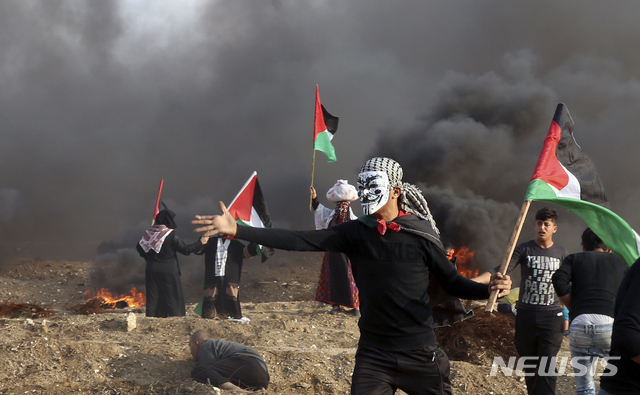 팔레스타인 시위자들이 9일(현지시간) 가자지구 동부 지역에서 국기를 흔들며 화염병을 준비하고 있다. 11일(현지시간) 밤 이스라엘군과 팔레스타인 무장 세력 하마스의 충돌로 하마스 대원 5명을 포함한 7명이 사망하고, 7명이 다쳤다. (출처: 뉴시스)