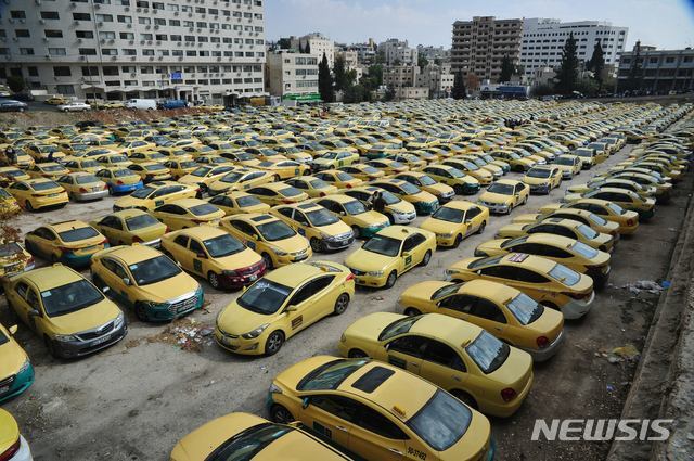 【암만(요르단)=뉴시스】 = 13일(현지시간) 요르단 택시기사들이 요르단 의회 앞에서 우버(Uber) 등 개인차량 앱 운송서비스에 대한 항의시위를 벌인 가운데 수백대의 택시들이 의회 인근 주차장에 줄지어 서 있다. 이들은 올해 6월과 10월 정식승인된 ‘카림(중동기반 앱 운송서비스)’과 우버의 운행규제를 강력히 요구하고 나섰다. 현재 요르단의 내,외국인들은 선명한 요금제와 서비스에 높은 만족도를 보이는 반면, 기존 택시 종사자들은 높은 택시면허 취득세(최소 6천3백만원)와 사납금 등으로 생존의 위협을 받고 있다며 강력히 반대하고 있다.