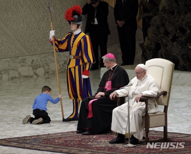【바티칸=AP/뉴시스】프란치스코 교황과 게오르크 겐스바인 주교가 28일(현지시간) 바티칸에서 열린 교황의 일반알현 도중 웬절 워스라는 6살 장애 소년이 연단 위로 올라와 교황을 경호하는 스위스 용병의 창을 만져보며 장난을 치는 모습을 웃으며 바라보고 있다. 프란치스코 교황은 워스에 대해 자유의 소중함을 알려주었다며 