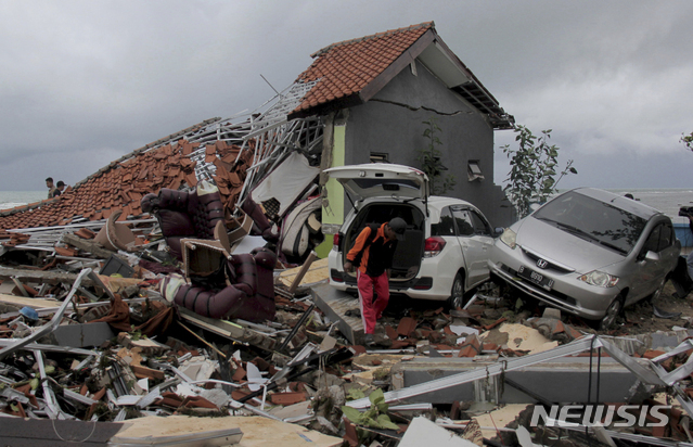 지난 22일 밤 인도네시아 순다해협 근처에서 발생한 쓰나미로 피해가 커지고 있는 가운데 24일 한 남성이 쓰나미가 덮친 건물을 수습하고 있다. (출처: 뉴시스)