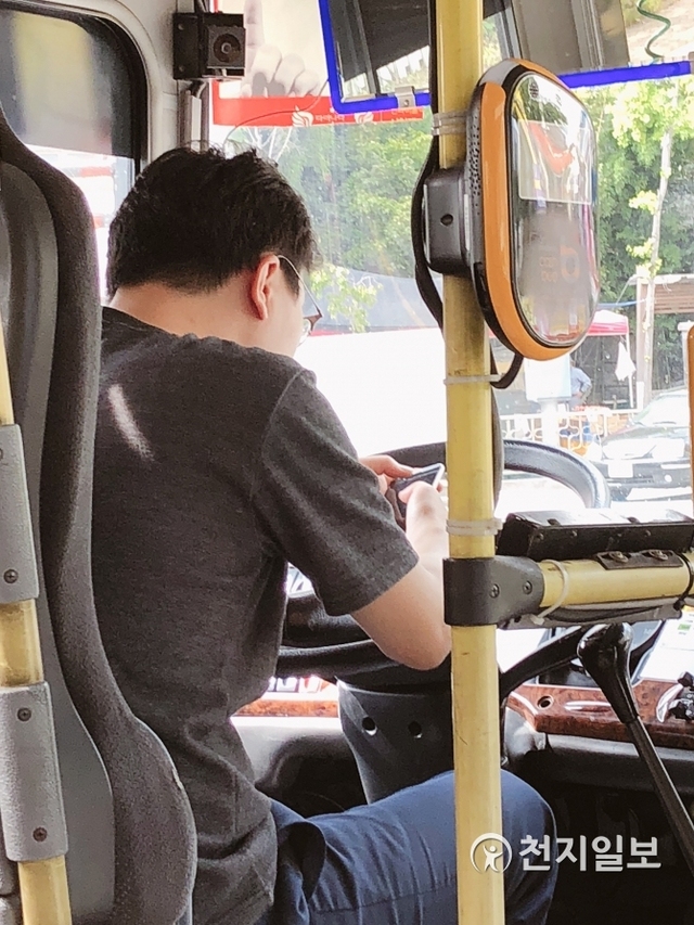 한 버스기사가 운전 중 시호대기에 걸려 휴대전화를 사용하고 있다. (출처: 경기도버스운송사업조합 홈페이지) ⓒ천지일보 2018.12.26