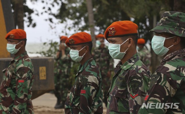 【카리타=AP/뉴시스】 28일(현지시간) 마스크를 착용한 인도네시아 군인들이 쓰나미 피해 지역인 카리타에서 파손된 가옥의 잔해물을 치우고 있다. 인도네시아 정부는 주민 안전을 위해 화산으로 촉발된 쓰나미 피해 인근 해안 출입금지 지역을 더 확장했다고 관계자가 밝혔다.