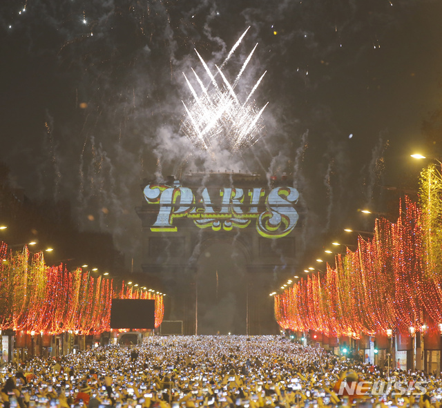 【파리=AP/뉴시스】1일(현지시간) 프랑스 파리의 샹젤리제 거리에 인파가 운집한 가운데 개선문 상공으로 새해 축하 불꽃이 화려하게 펼쳐지고 있다.