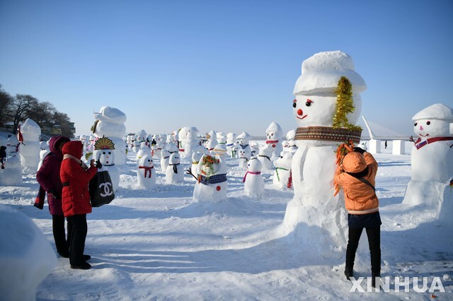 2일(현지시간) 관광객들이 중국 헤이룽장성 하얼빈의 쑹화강둑에 만들어진 눈사람 무리를 감상하고 있다. (출처: 뉴시스)