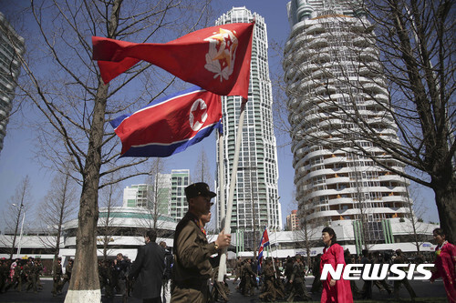북한 평양 려명거리 준공식. 군인들이 인공기 등을 들고 걸어가는 모습. (출처: 뉴시스)